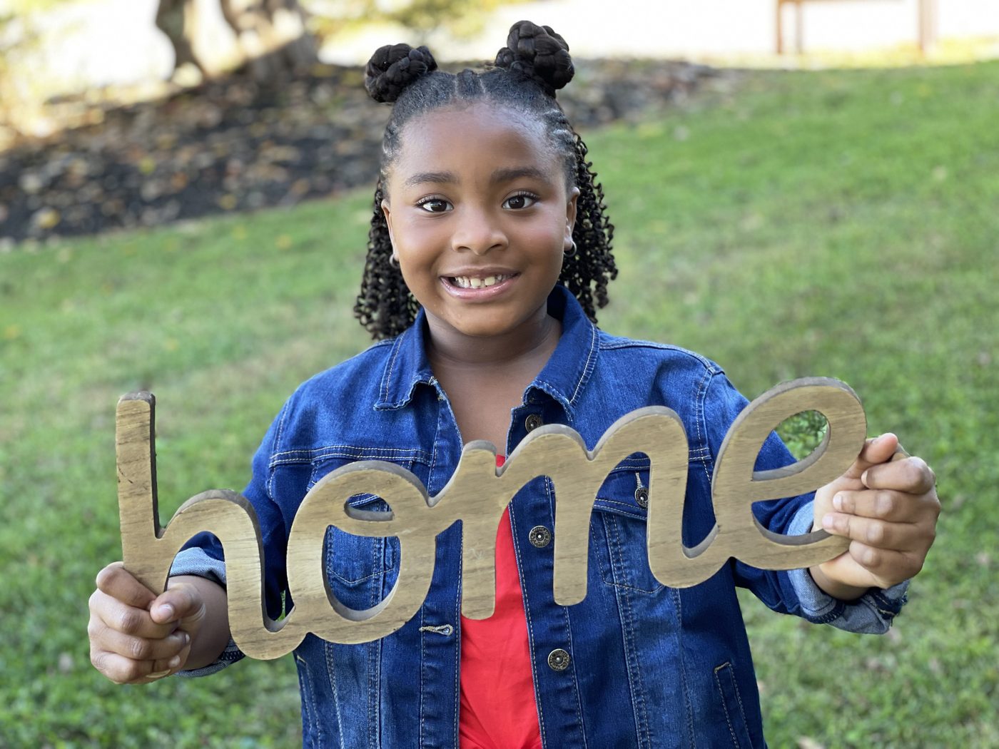 Quantella's daughter holding a wooden HOME sign